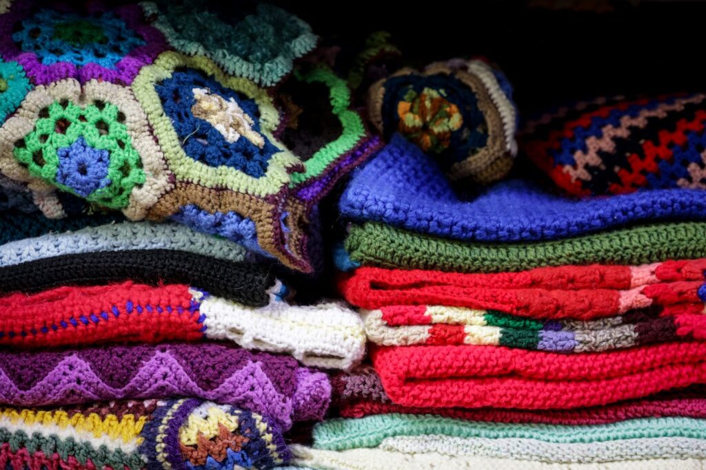 Stack of colorful handmade crochet and knitted blankets