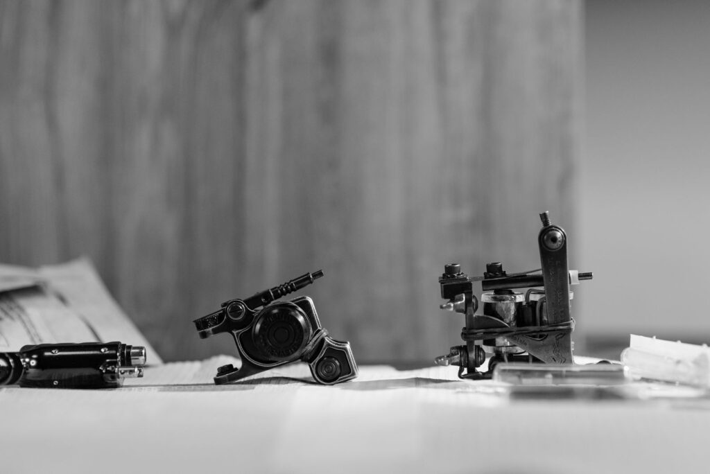Two coil tattoo machines resting on a studio table in black and white