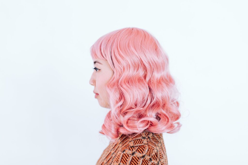 Woman in profile with wavy pastel pink hair