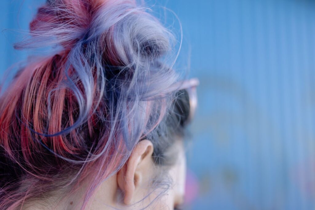 Messy bun of hair dyed in pastel purple, blue and pink tones